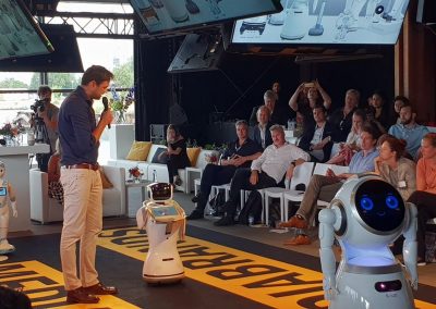 Spreker met robots op het podium